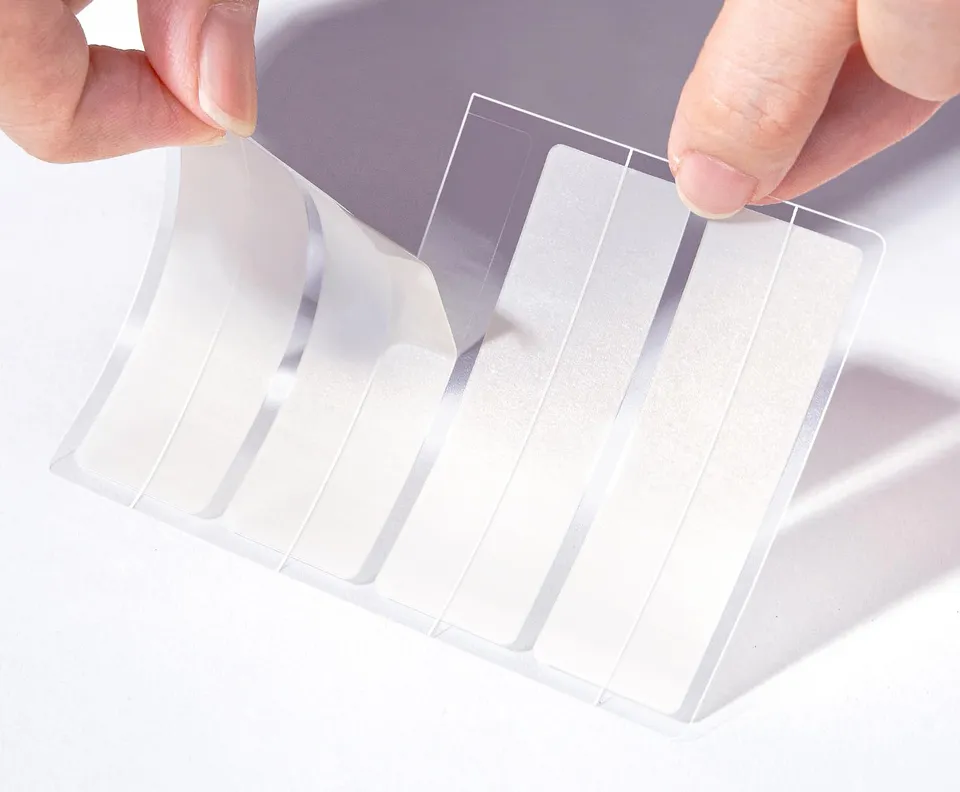 A hand peeling a long TKTK hydrocolloid strip from its sheet